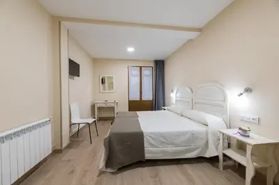 a bedroom with a white bed and a desk at Pensión Luis in Arzúa
