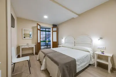 a bedroom with a white bed and a chair at Pensión Luis in Arzúa