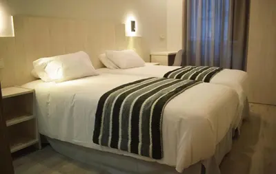 a bedroom with a large bed with white sheets and pillows at Santa Filomena in Santiago de Compostela