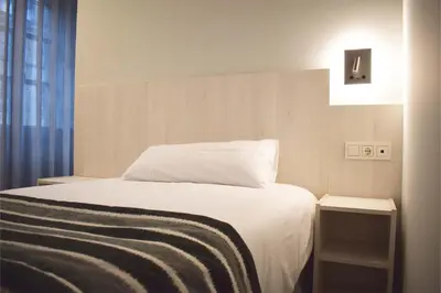 a bedroom with a white bed and a window at Santa Filomena in Santiago de Compostela