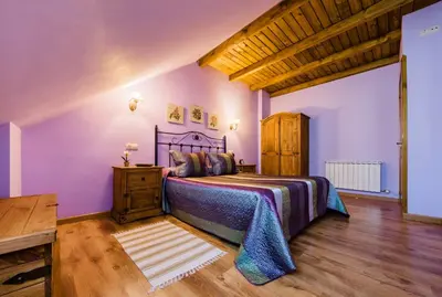 a bedroom with a bed with purple walls and wooden floors at Apartamentos Rurales L´Abiseu in Caboalles de Abajo