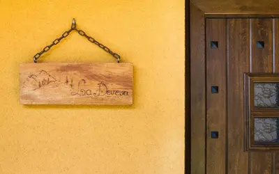 a wooden sign hanging on a wall next to a door at Apartamentos Rurales L´Abiseu in Caboalles de Abajo