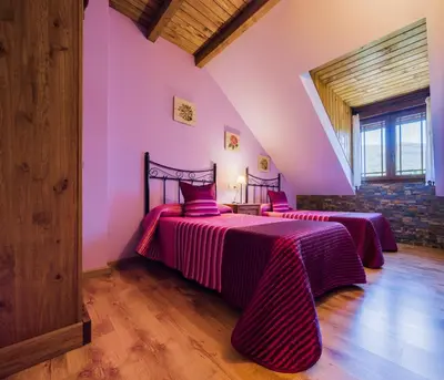 two beds in a room with pink walls and wooden floors at Apartamentos Rurales L´Abiseu in Caboalles de Abajo