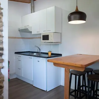 a kitchen with white cabinets and a wooden table at Alojamientos rurales O Acivro in A Rúa