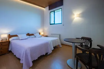 a bedroom with two beds and a table and a window at Alojamientos rurales O Acivro in A Rúa