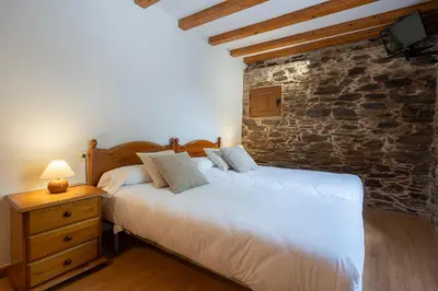 two beds in a bedroom with a stone wall at Alojamientos rurales O Acivro in A Rúa