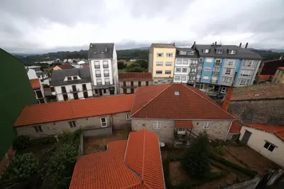 a group of buildings with red roofs in a city at Pension Pardellas in Palas de Rei