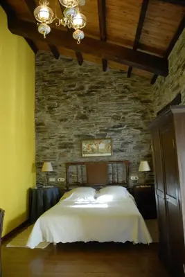 a bedroom with a large bed in a stone wall at Casa Grande da Ferreria de Rugando in Rugando