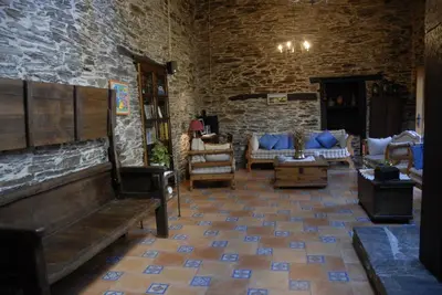 a living room with couches and a stone wall at Casa Grande da Ferreria de Rugando in Rugando