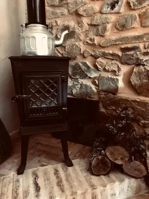 a stove in a room with a stone wall at The Pilgrim Stone - Vegan B&B in Rabanal del Camino