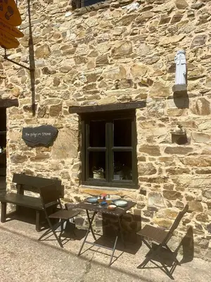 a table and two chairs next to a stone building at The Pilgrim Stone - Vegan B&B in Rabanal del Camino