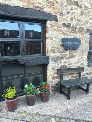 a bench in front of a stone building with potted plants at The Pilgrim Stone - Vegan B&B in Rabanal del Camino