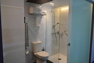 a bathroom with a toilet and a glass shower at Hotel Alda Estación Ourense in Ourense