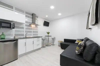 a living room with a black couch and a kitchen at La Pause in Arzúa
