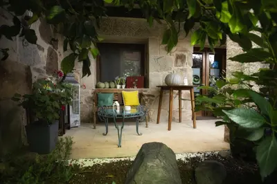 a patio with chairs and a table in a stone building at Casa Ramiras in O Viso