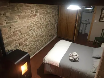 a bedroom with a bed and a stone wall at Casa Rural del Acebo in Espinoso de Compludo