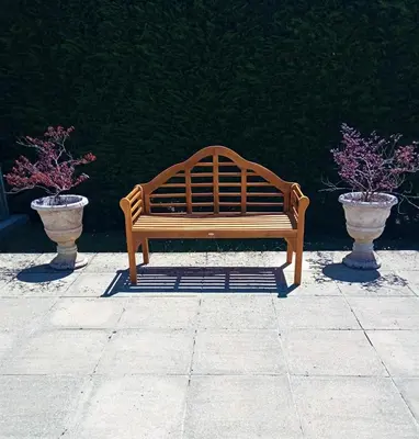 a wooden bench sitting on a sidewalk next to two vases at As Seis Chemineas in San Xulián de Sales