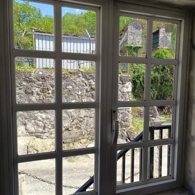 an open window looking out at a stone wall at Pensión Rural para Peregrinos 