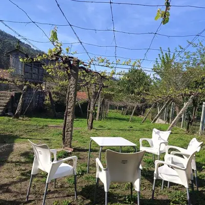 a group of white chairs and tables in a field at Pensión Rural para Peregrinos 