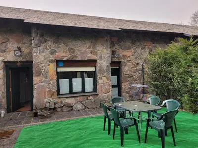 a patio with a table and chairs on a green lawn at El Relax de Sanabria in Trefacio