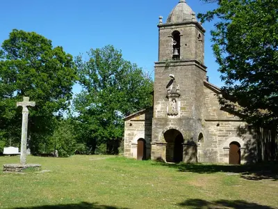 an old stone church with a cross in a field at El Relax de Sanabria in Trefacio