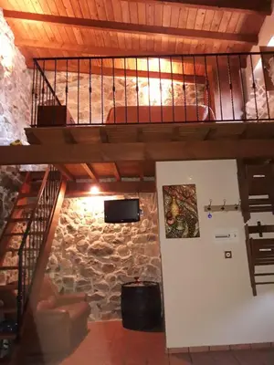 a loft bed in a room with a stone wall at Loft Corte de Fora in Ourense