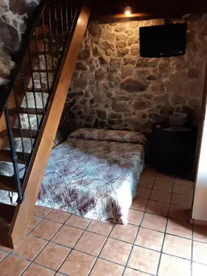 a bed in a room with a stone wall at Loft Corte de Fora in Ourense