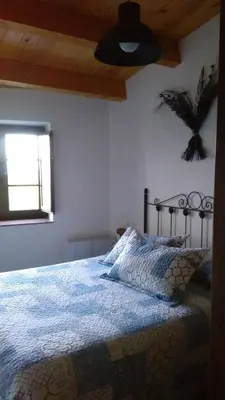 a bedroom with a bed with a blue blanket and a window at A Minguxaina in Ribadeo