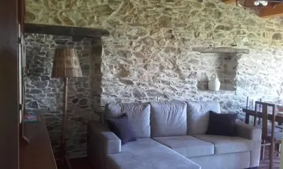 a living room with a couch against a stone wall at A Minguxaina in Ribadeo