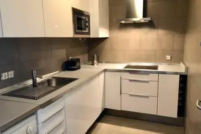a kitchen with white cabinets and a sink and a microwave at La Casa de Antón in Tineo
