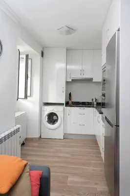 a kitchen with white cabinets and a washer and dryer at Apartamento Algalia Catedral in Santiago de Compostela