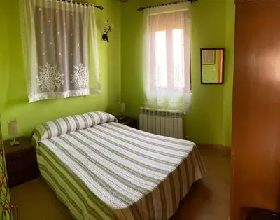 a bedroom with a bed with green walls and windows at El Mirador del Bierzo in Tedejo