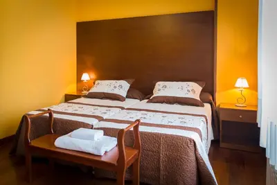 a bedroom with a large bed with two chairs and two lamps at Pension ARCA in O Pedrouzo