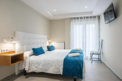 a bedroom with a large bed with blue pillows at Pension ARCA in O Pedrouzo