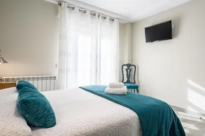 a bedroom with a bed with a blue blanket on it at Pension ARCA in O Pedrouzo