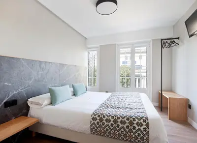 a bedroom with a large white bed with blue pillows at PR 25 de Julio in Santiago de Compostela
