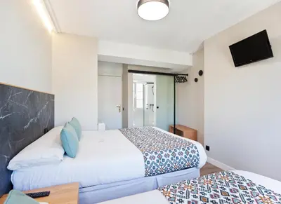 a hotel room with two beds and a tv at PR 25 de Julio in Santiago de Compostela