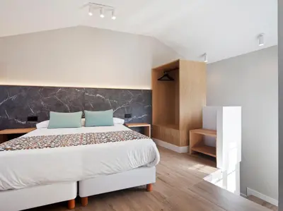 a bedroom with a large white bed with blue pillows at PR 25 de Julio in Santiago de Compostela