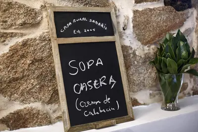 a chalkboard sign sitting on a table with a vase at Casa de Turismo Rural Sabariz in Sabariz