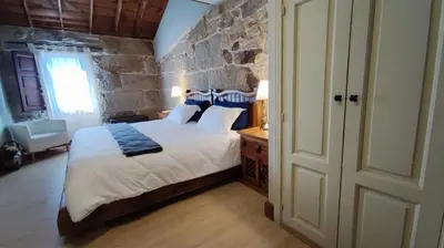 a bedroom with a bed and a stone wall at Casa de Turismo Rural Sabariz in Sabariz