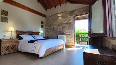 a bedroom with a bed and a stone wall at Casa de Turismo Rural Sabariz in Sabariz