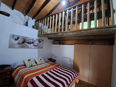 a bedroom with a bed and a wooden staircase at La Casa de las Rocas - En la Ribeira Sacra in Nogueira de Ramuin