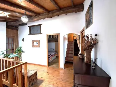 a living room with a staircase and a table with flowers at La Casa de las Rocas - En la Ribeira Sacra in Nogueira de Ramuin