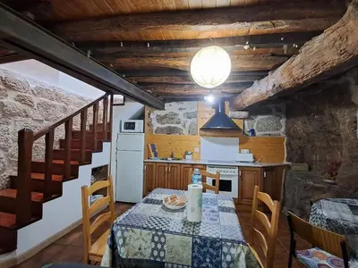 a kitchen with a table and a kitchen with a staircase at La Casa de las Rocas - En la Ribeira Sacra in Nogueira de Ramuin