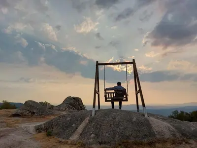 a man sitting on a swing on a rock at La Casa de las Rocas - En la Ribeira Sacra in Nogueira de Ramuin