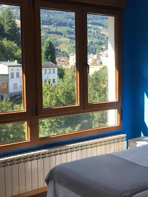 a bedroom with three windows with a view at Narcea Turismo Real in Cangas del Narcea