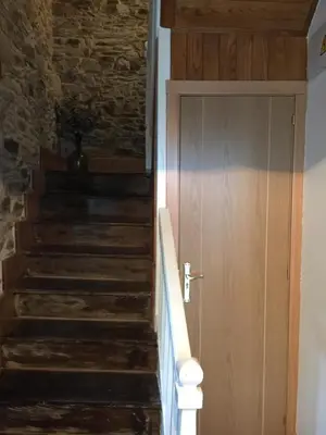 a staircase with a wooden door and a stone wall at Narcea Turismo Real in Cangas del Narcea