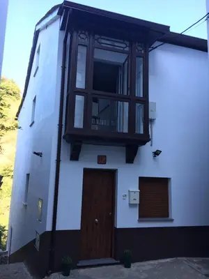 a white building with a window and a door at Narcea Turismo Real in Cangas del Narcea
