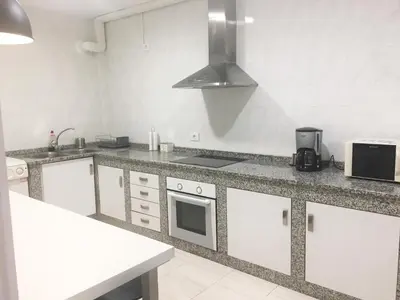 a kitchen with white cabinets and a stove top oven at Apartamento Barrio San Pedro in Santiago de Compostela