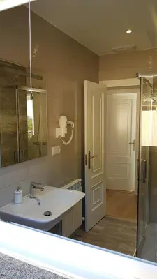 a bathroom with a sink and a mirror and a door at PortoHouse in Portomarin